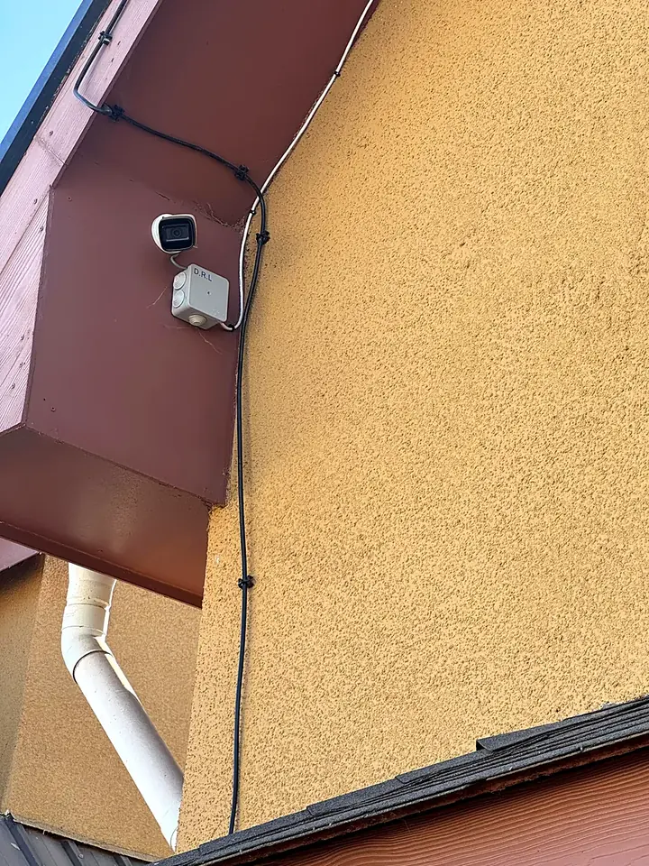 Cámara bala con caja estanca en el alero de una casa, con el cable fijado con clips