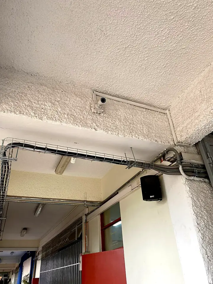 Cámara instalada en el pasillo de un colegio, con el cable llevado por canaleta
